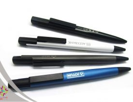 Four branded promotional ballpoint pens: black, white, gray, and blue.