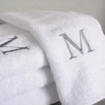 Stack of white terry cloth towels embroidered with a luxury initial 'M'.