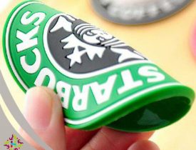 Flexible green Starbucks logo rubber coaster held by fingers.