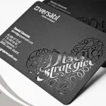 Premium black business card with intricate die-cut scrollwork and white text.