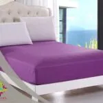 Vibrant purple linen on a luxurious bed with an ocean view.
