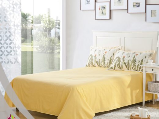 Bright modern bedroom with yellow linen, botanical print pillows, and garden view.