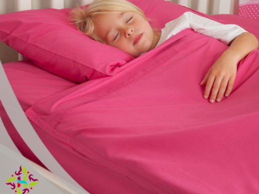 Young child sleeping peacefully on vibrant hot pink linen bedding.