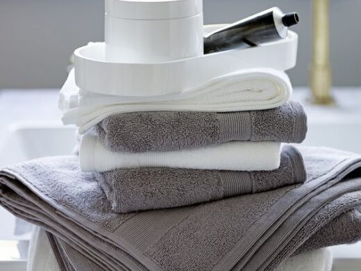 Neatly stacked white and gray plush bath towels in a luxurious bathroom setting.