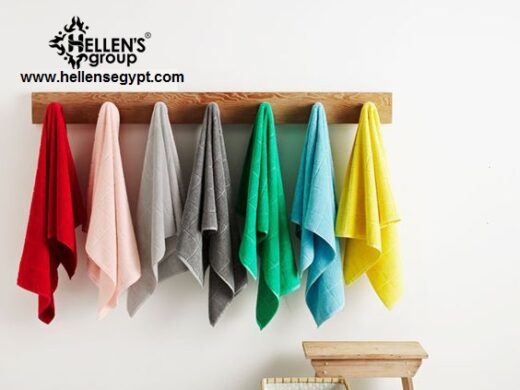 Colorful bath towels hanging on a wooden rack in a modern, bright bathroom setting.