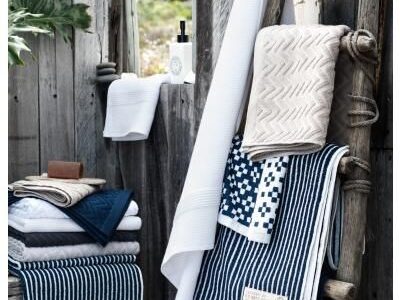 High-quality striped and woven bath towels displayed in a rustic coastal setting.