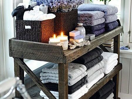Rustic bathroom shelving with colorful and gray stacked towels, lavender, and candles.