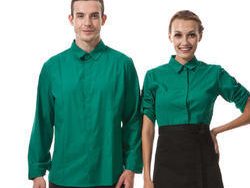 Smiling hotel staff in matching emerald green uniform shirts and black aprons.