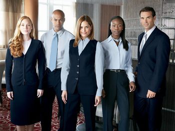 Professional hotel staff in business attire standing on patterned carpet.
