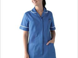 Smiling nurse in bright blue uniform tunic with white trim, standing against white.