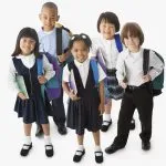 Diverse elementary students in navy blue school uniforms with colorful backpacks ready for school.